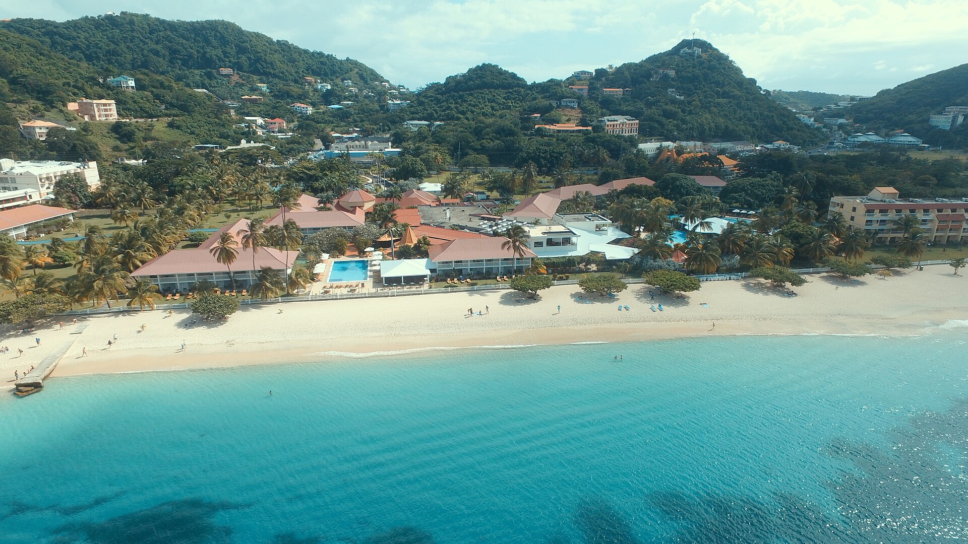 Grand Anse Beach in Grenada in daylight, with the bay, resorts and green hills behind