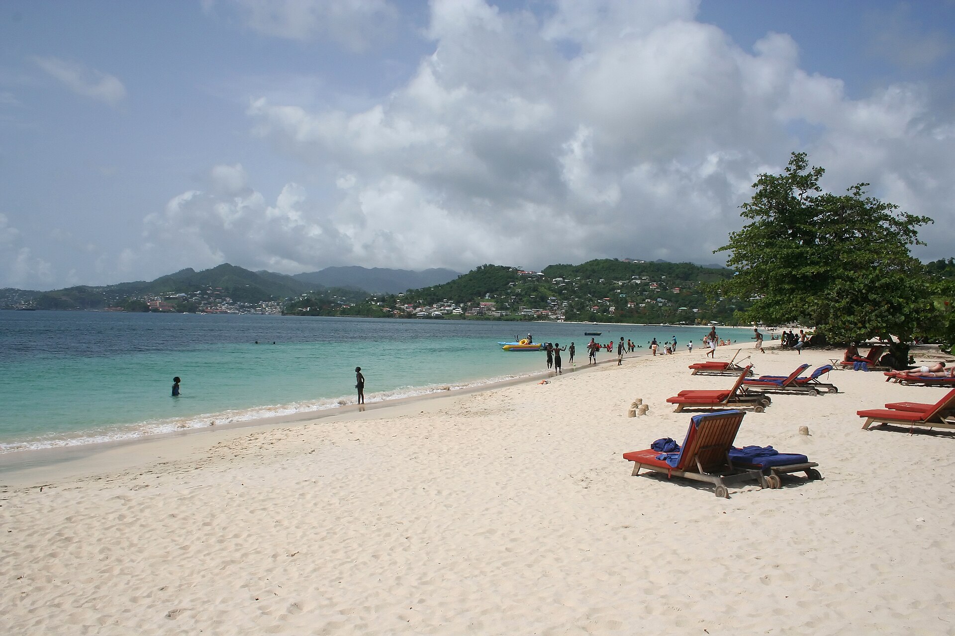 Loungers and swimmers on the white sand at Grand Anse beach, Grenada, on a bright day