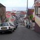 A steep narrow street in St. George's, Grenada, dropping towards the harbour with cars parked along it