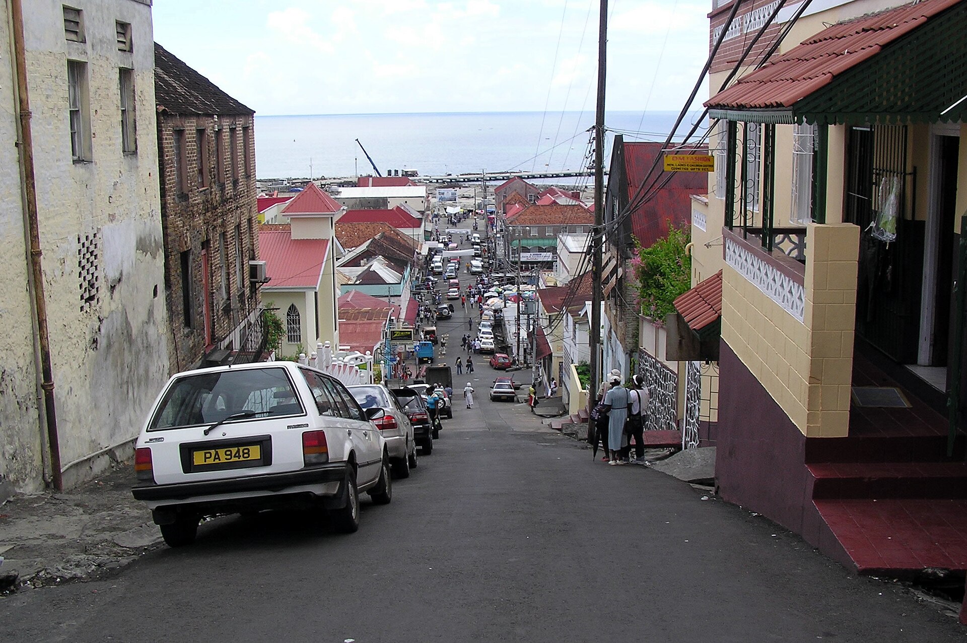 A steep narrow street in St. George's, Grenada, dropping towards the harbour with cars parked along it